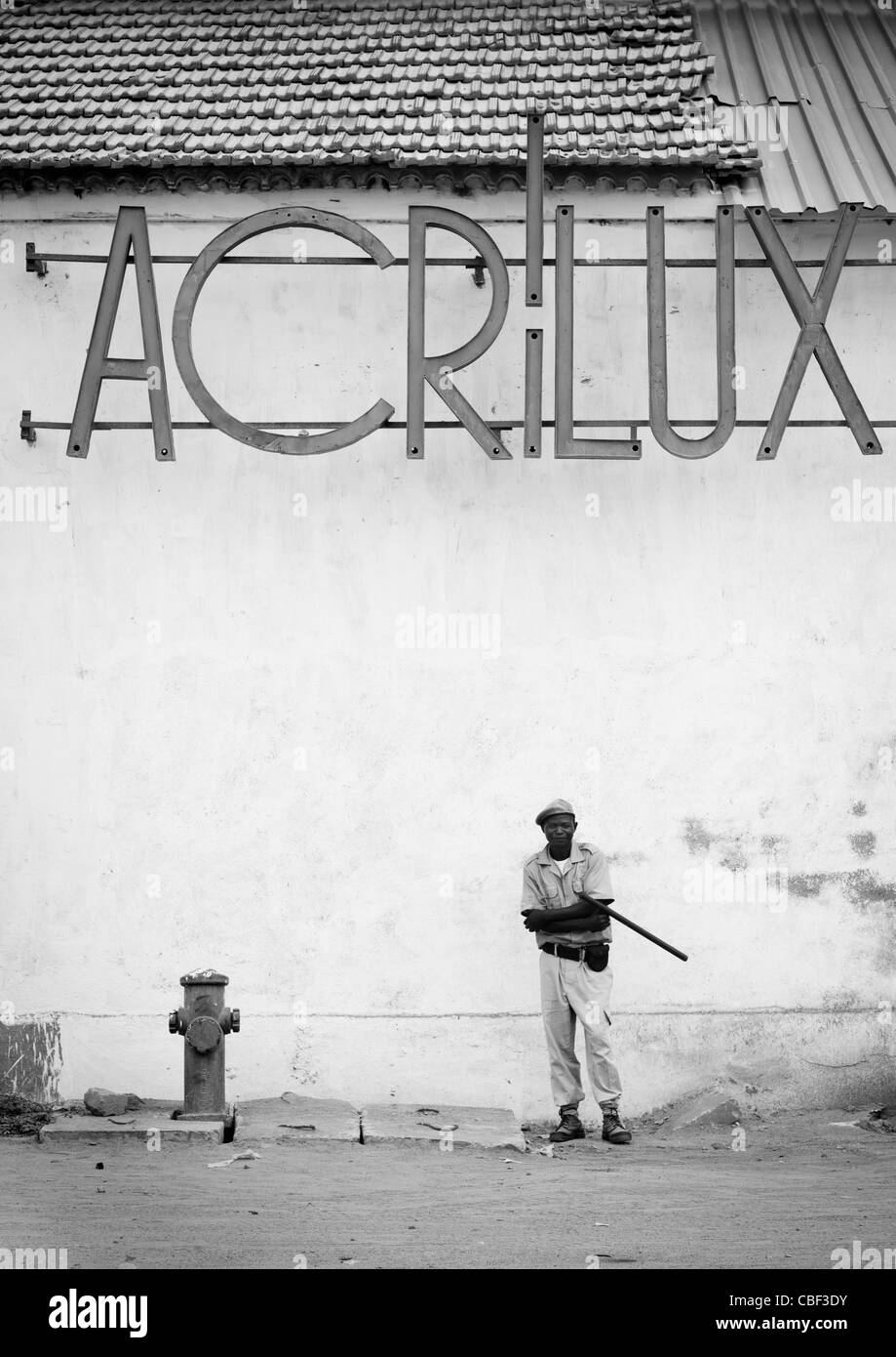 Policier en face d'un vieux magasin Acrilux, Benguela, Angola Banque D'Images