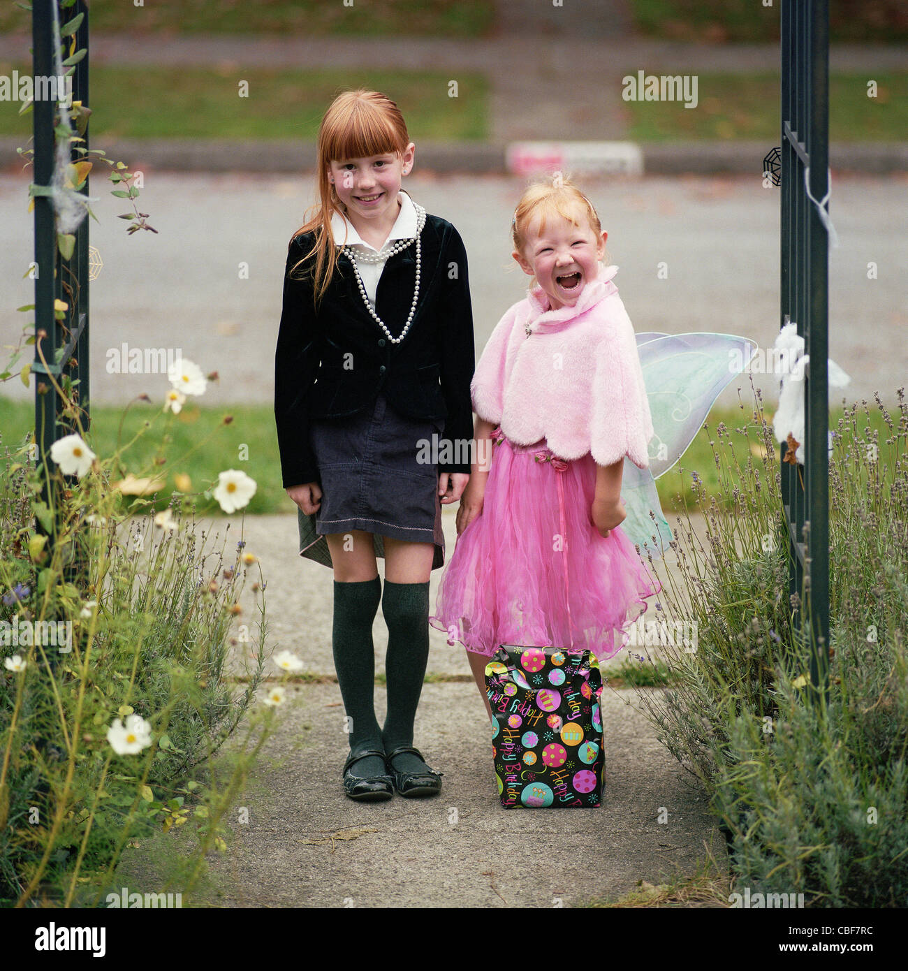 Deux enfants jouant à l'extérieur - fille soeurs jouer à s'habiller et posant dans le jardin Banque D'Images