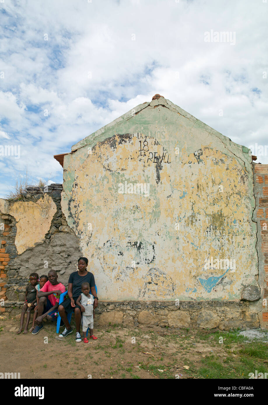 Famille assis devant leur maison délabrée, Bilaiambundo, Angola Banque D'Images