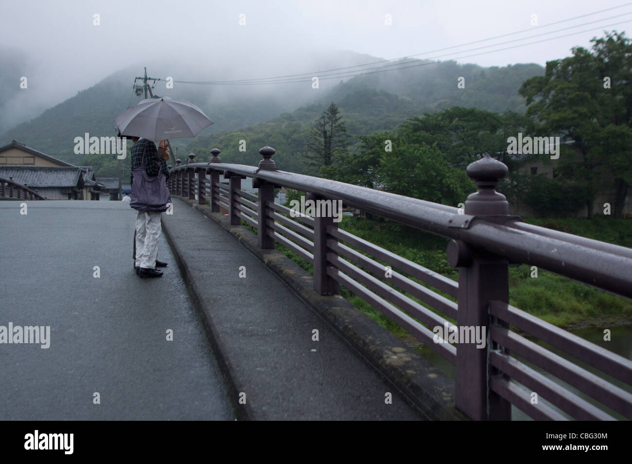 Les refuges d'une femme sous un parapluie sur un pont de l'Ise, Japon Banque D'Images