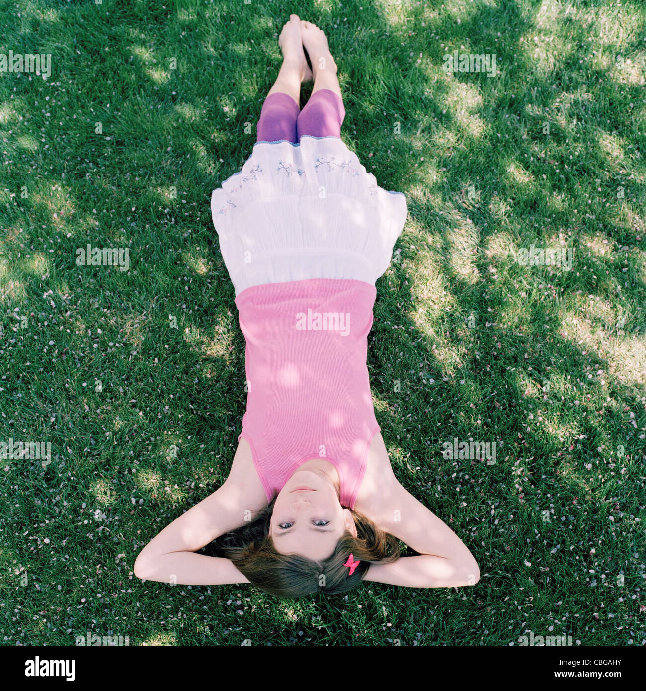 Une jeune fille allongée dans l'herbe avec les mains derrière la tête, à l'envers afficher Banque D'Images