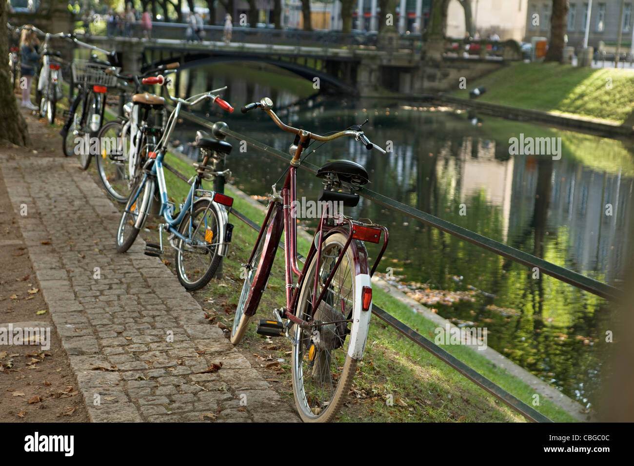 Cinq bicyclettes garées dans une rangée à côté d'une rivière Banque D'Images