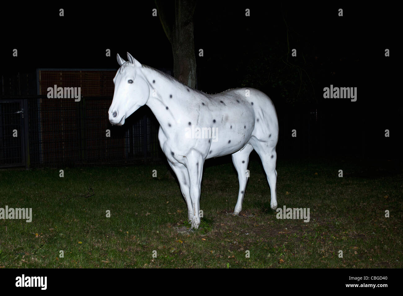 Cheval blanc sur l'herbe artificielle décorée avec des points noirs Banque D'Images