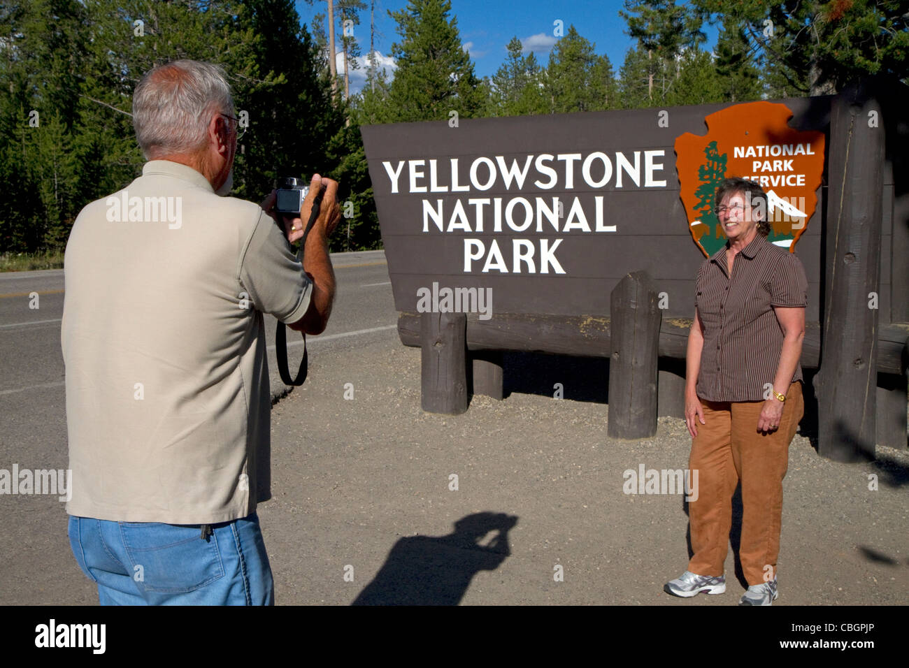 Les touristes de prendre une photo en face de l'entrée du Parc National de Yellowstone, West Yellowstone, Montana, USA. Banque D'Images