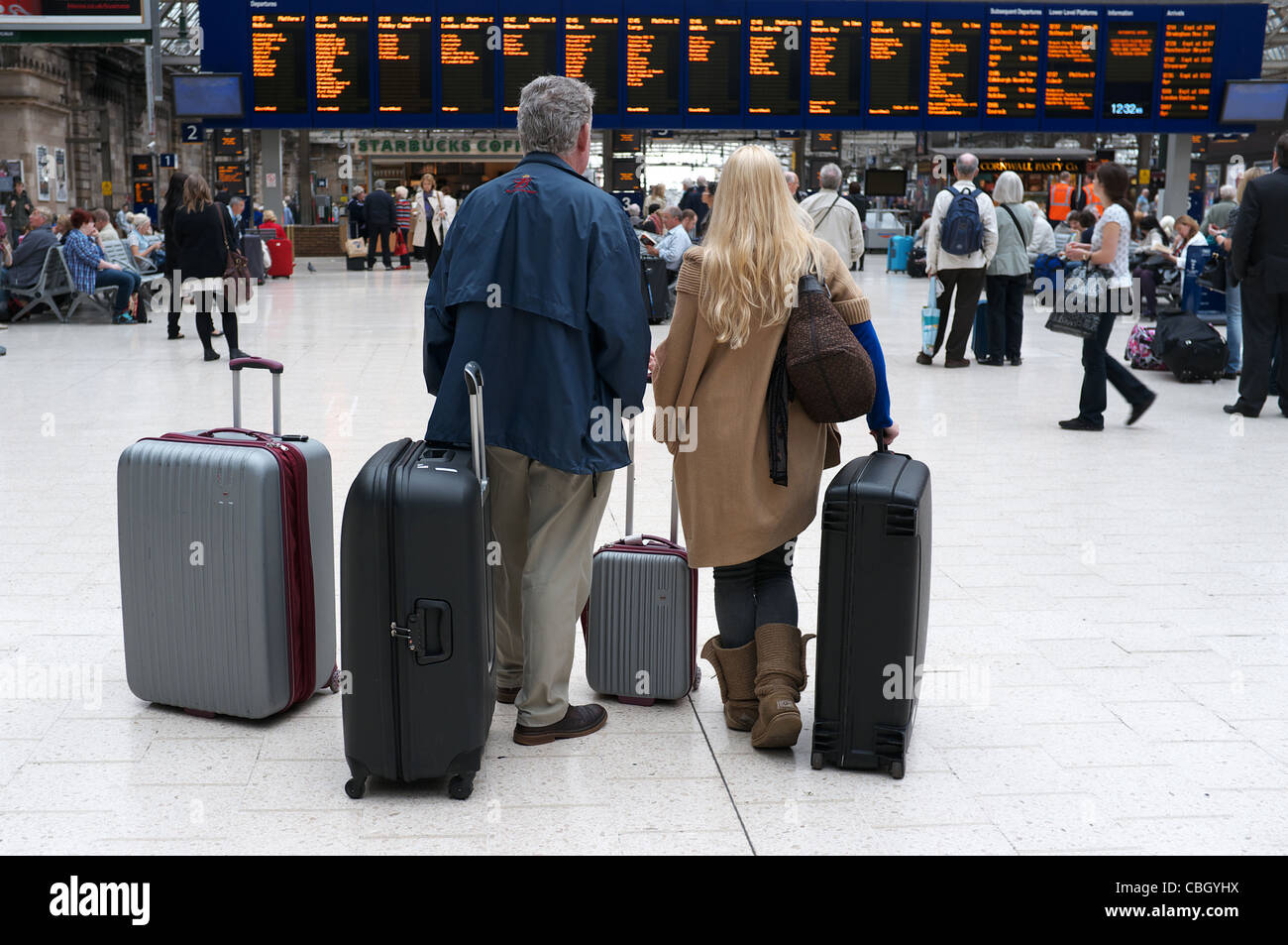 L'homme et de la femme avec des valises en attente à la gare centrale de Glasgow, regardant les cartes Destination, Glasgow, Écosse, Royaume-Uni Banque D'Images