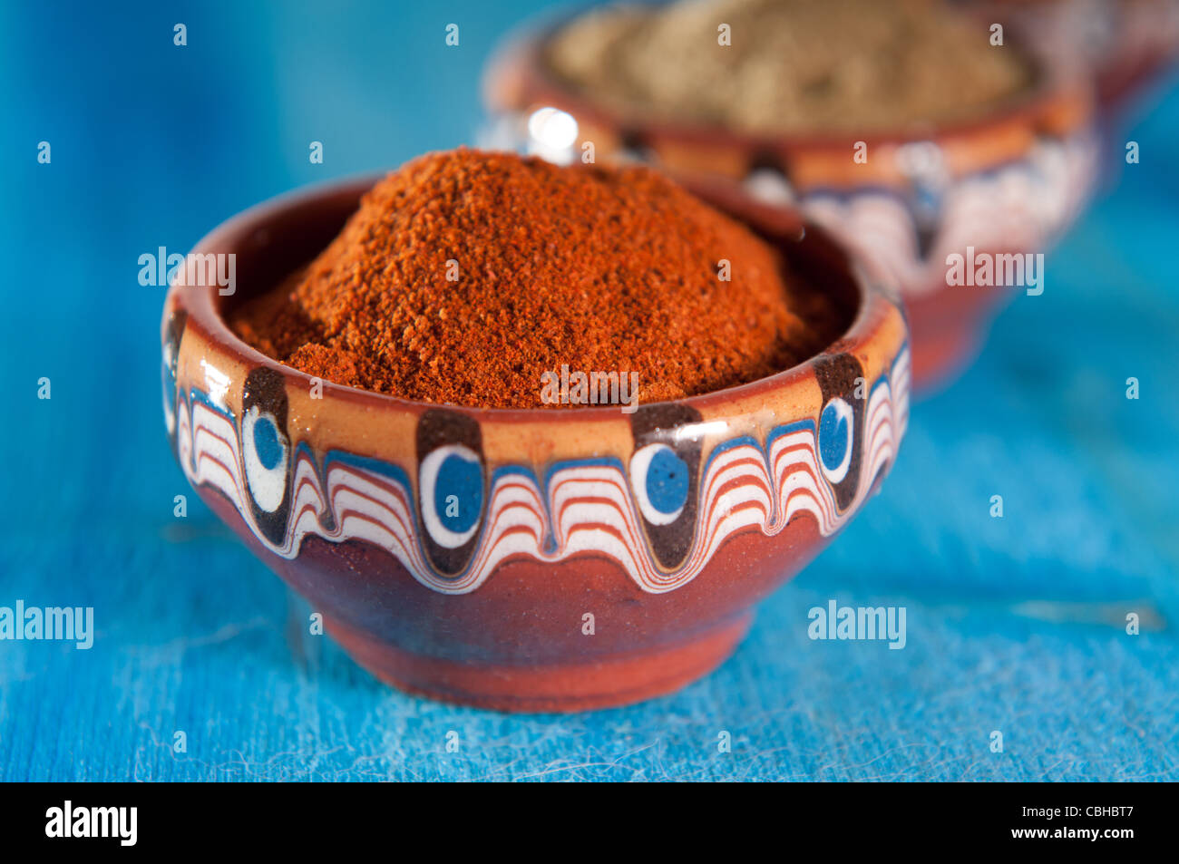 Le poivre rouge, le sel et la sarriette dans bols de céramique traditionnelle bulgare sur fond bleu Banque D'Images
