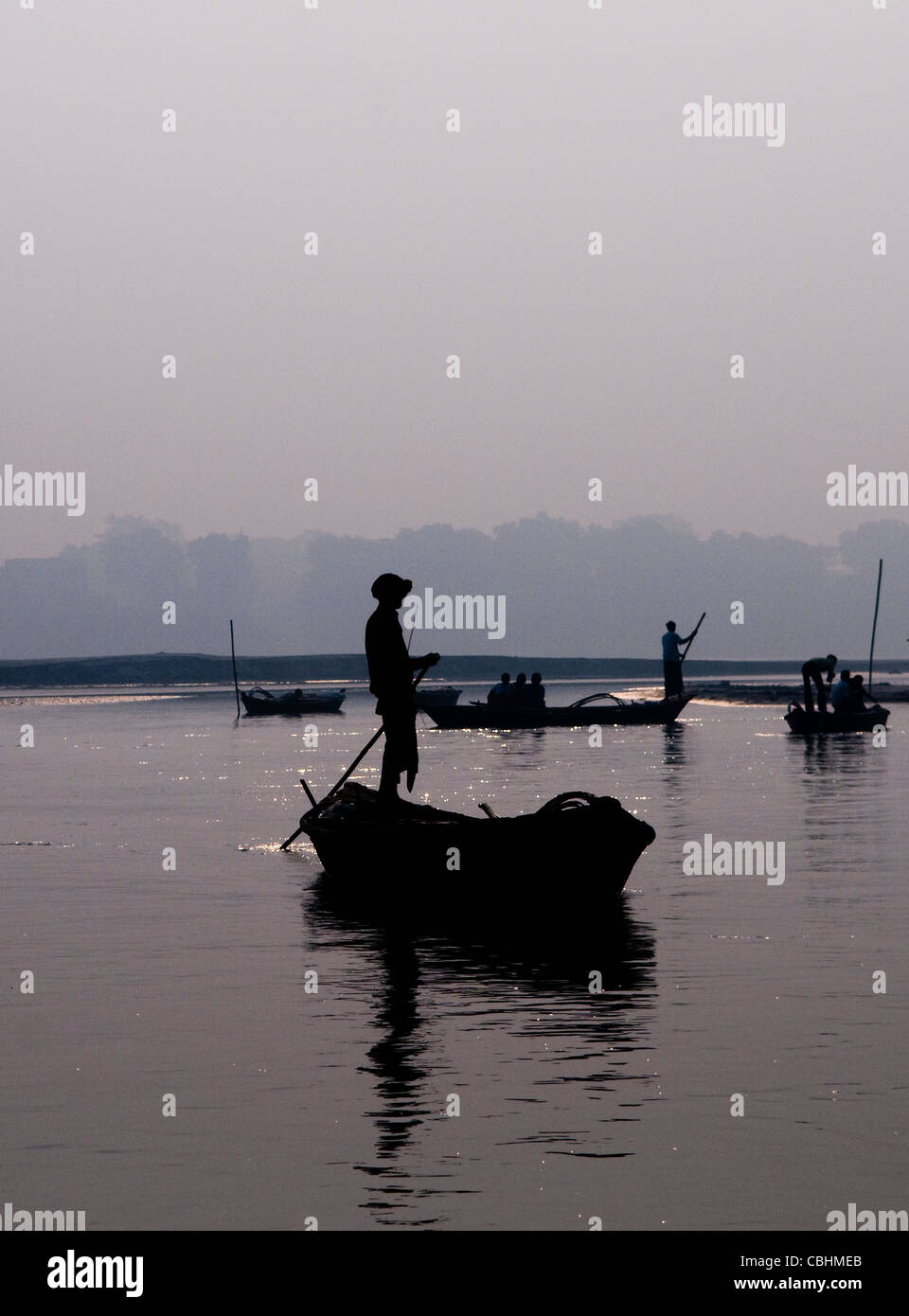 Un pêcheur indien son bateau aviron pendant le lever du soleil sur le fleuve Gandak dans Bihar. Banque D'Images