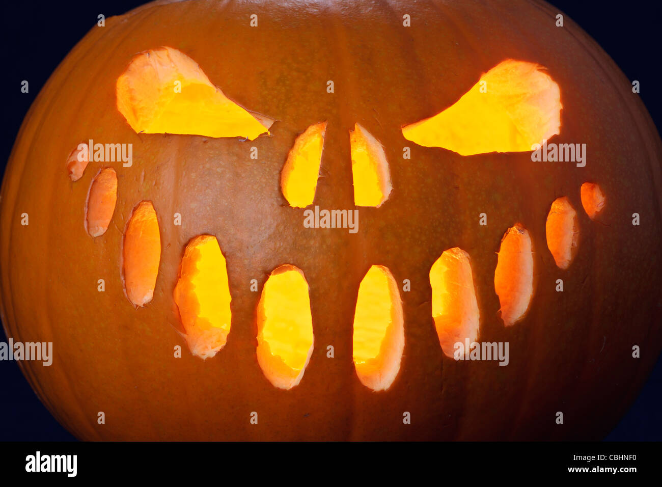 Gros plan d'une citrouille halloween jack-o-lanterne allumée avec bougie à l'intérieur Banque D'Images