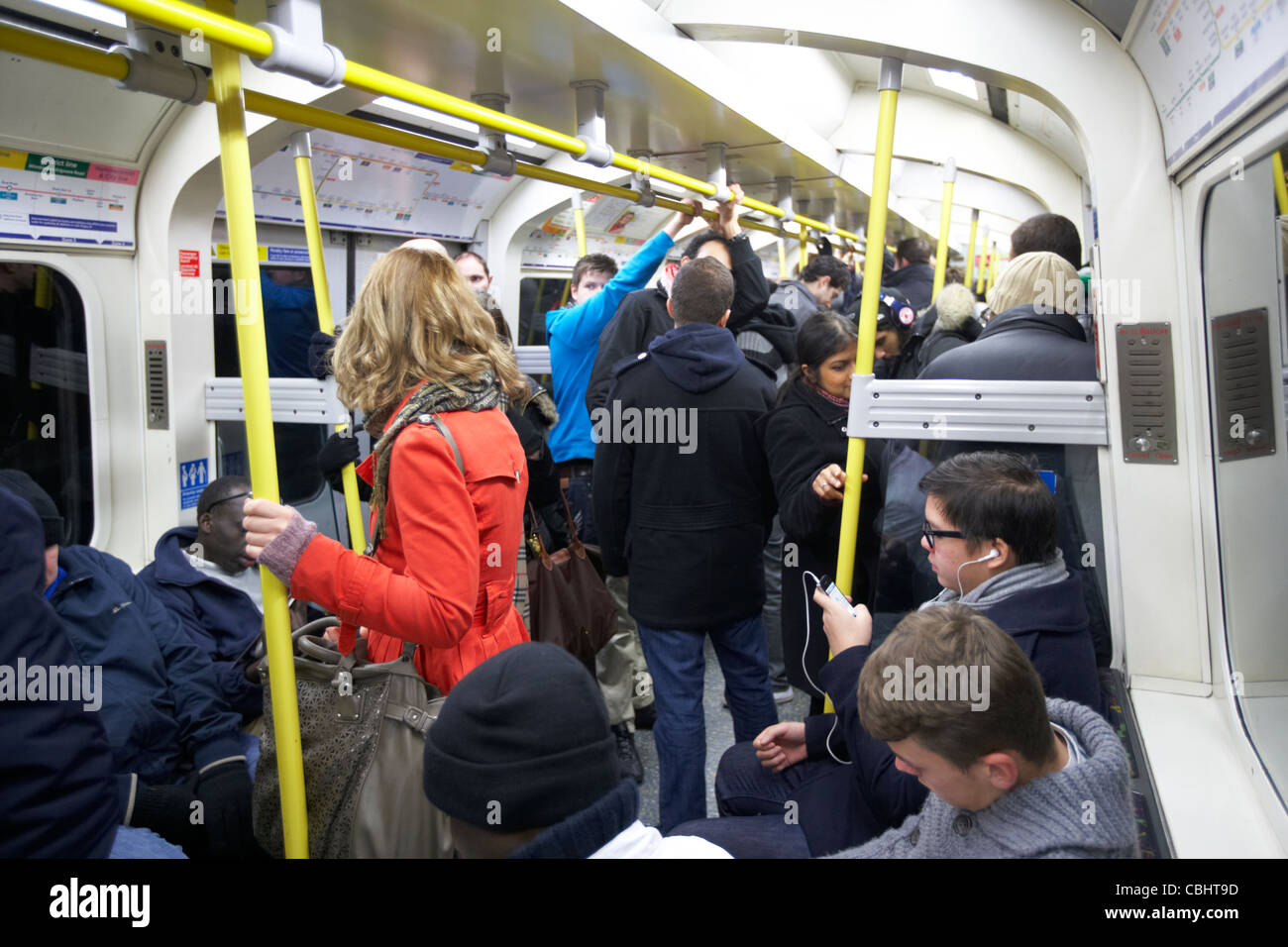 Fille avec manteau rouge debout sur occupation train de tube entouré par des gens sur le métro de Londres Angleterre Royaume-Uni uk Banque D'Images