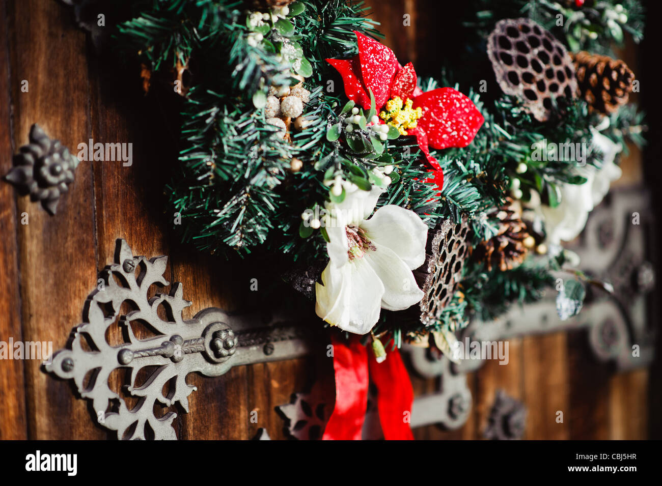 Détail d'une couronne de Noël accroché sur une vieille porte en bois, avec des charnières en métal Banque D'Images