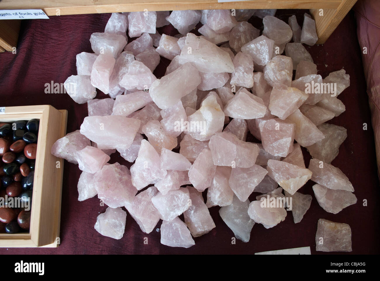 Amas de cristaux de quartz rose rose en vente sur un tissu rouge sur un étal du marché la vente de spécimens géologiques Banque D'Images