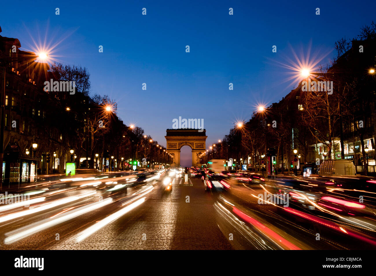 Un grand angle de vue Arc de Triomphe des Champs Elysées en soirée, avec des sentiers de lumière de la circulation. Banque D'Images