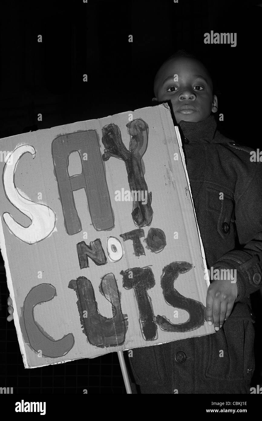 Jeune garçon noir est titulaire d'une plaque qui lit «Dites non aux compressions budgétaires". Banque D'Images