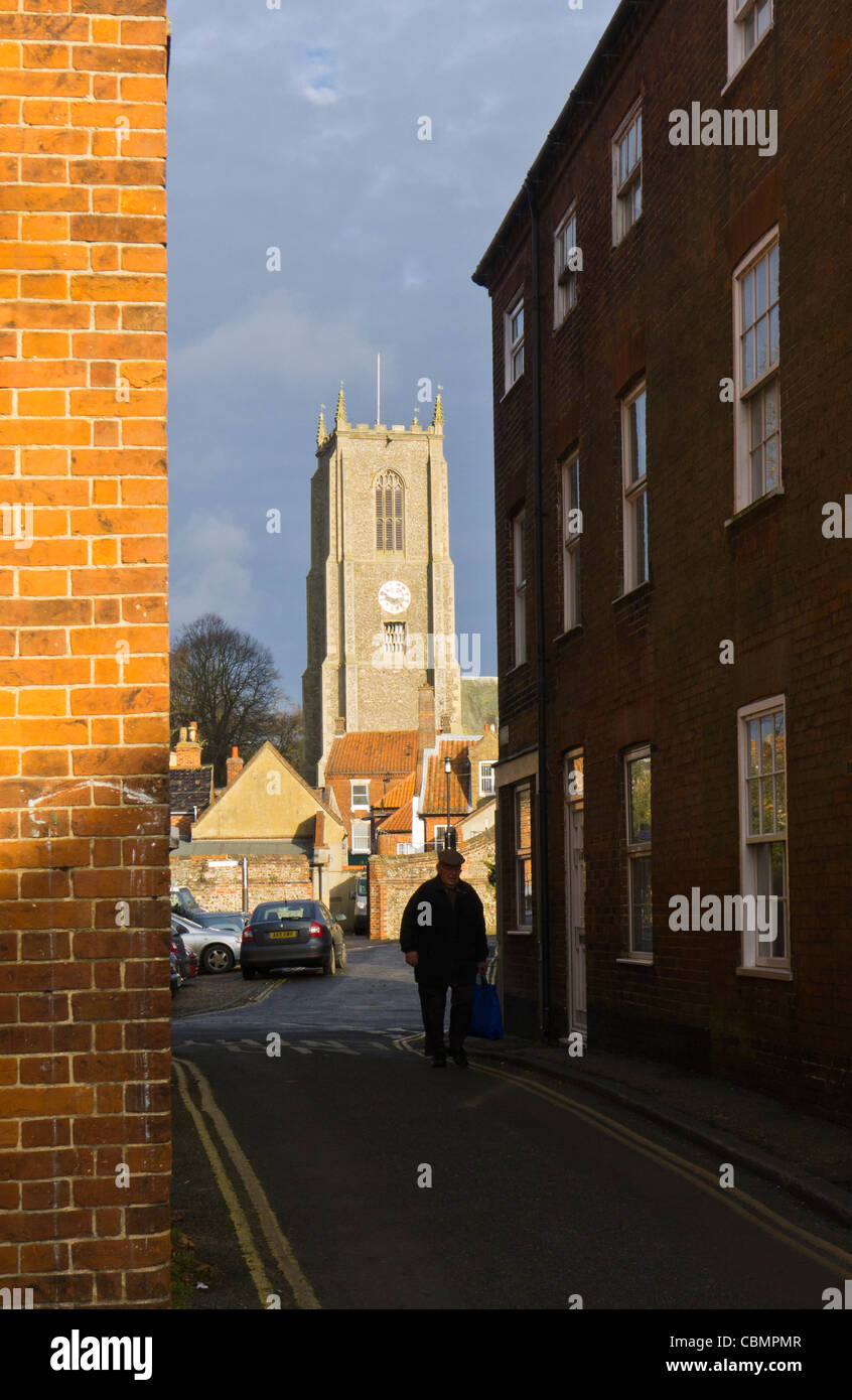 Un homme marchant avec un sac shopping en Fakenham, Norfolk. Banque D'Images