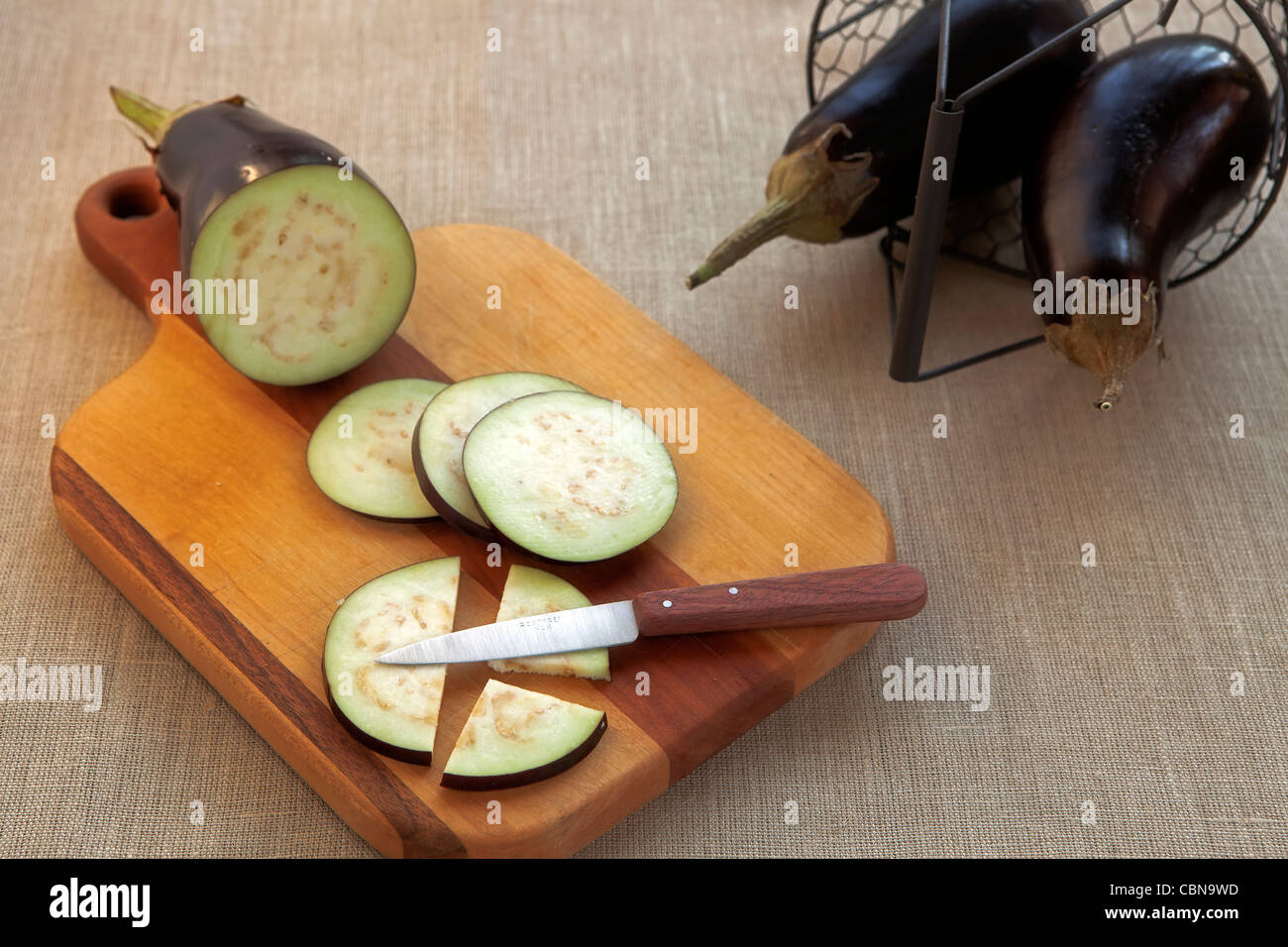 Ensemble, l'aubergine et couper avec un couteau sur une planche en bois Banque D'Images