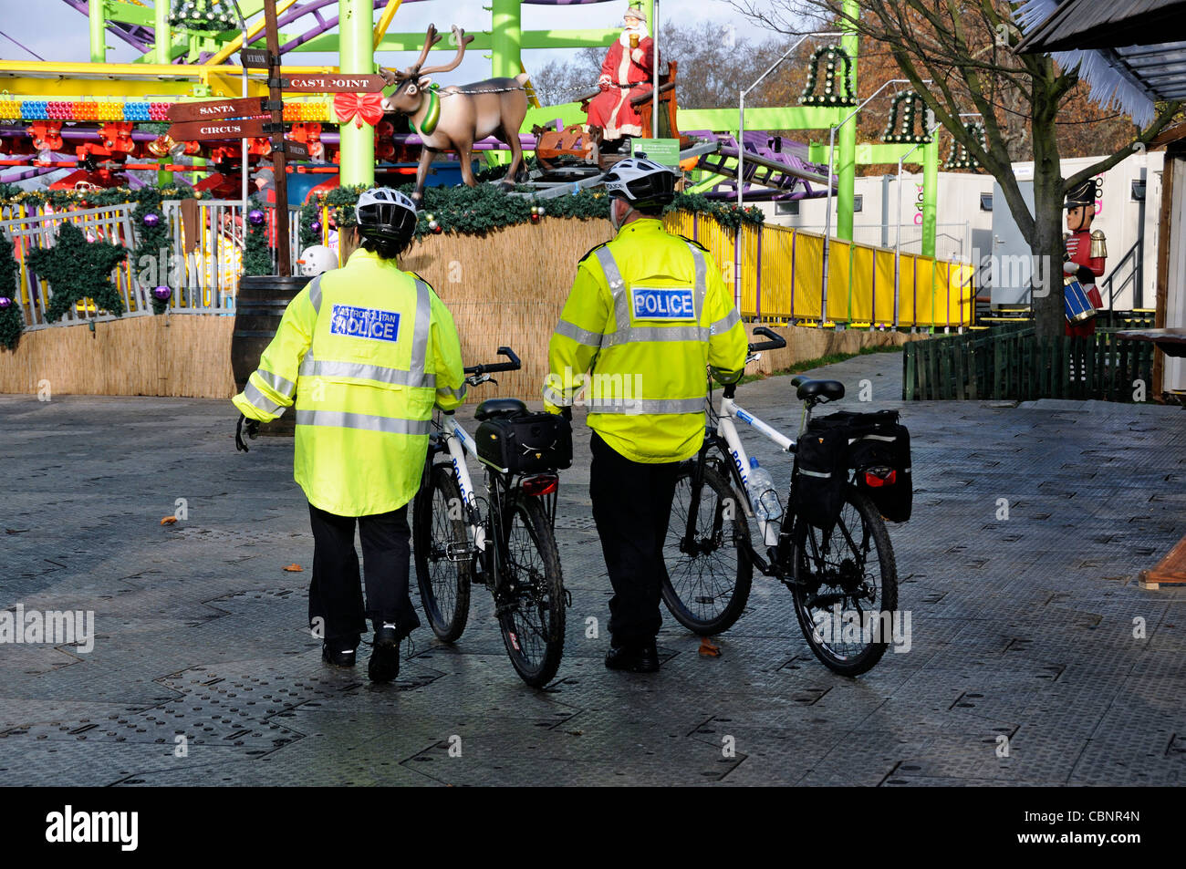 Agents de la Police métropolitaine avec des vélos à la féerie d'hiver fête foraine Banque D'Images