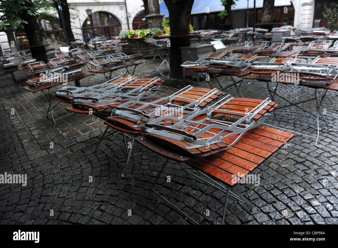 Sièges recouverts de pluie au beer garden Munich Bavaria Allemagne Munchen Deutschland Banque D'Images