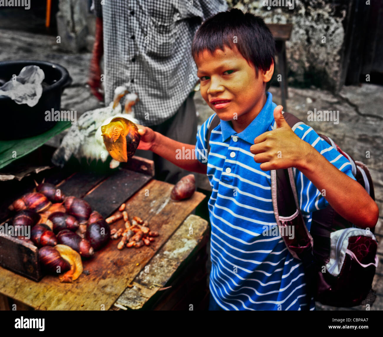 Jeune garçon tenant un escargot géant au marché de Belen Iquitos Perou Banque D'Images