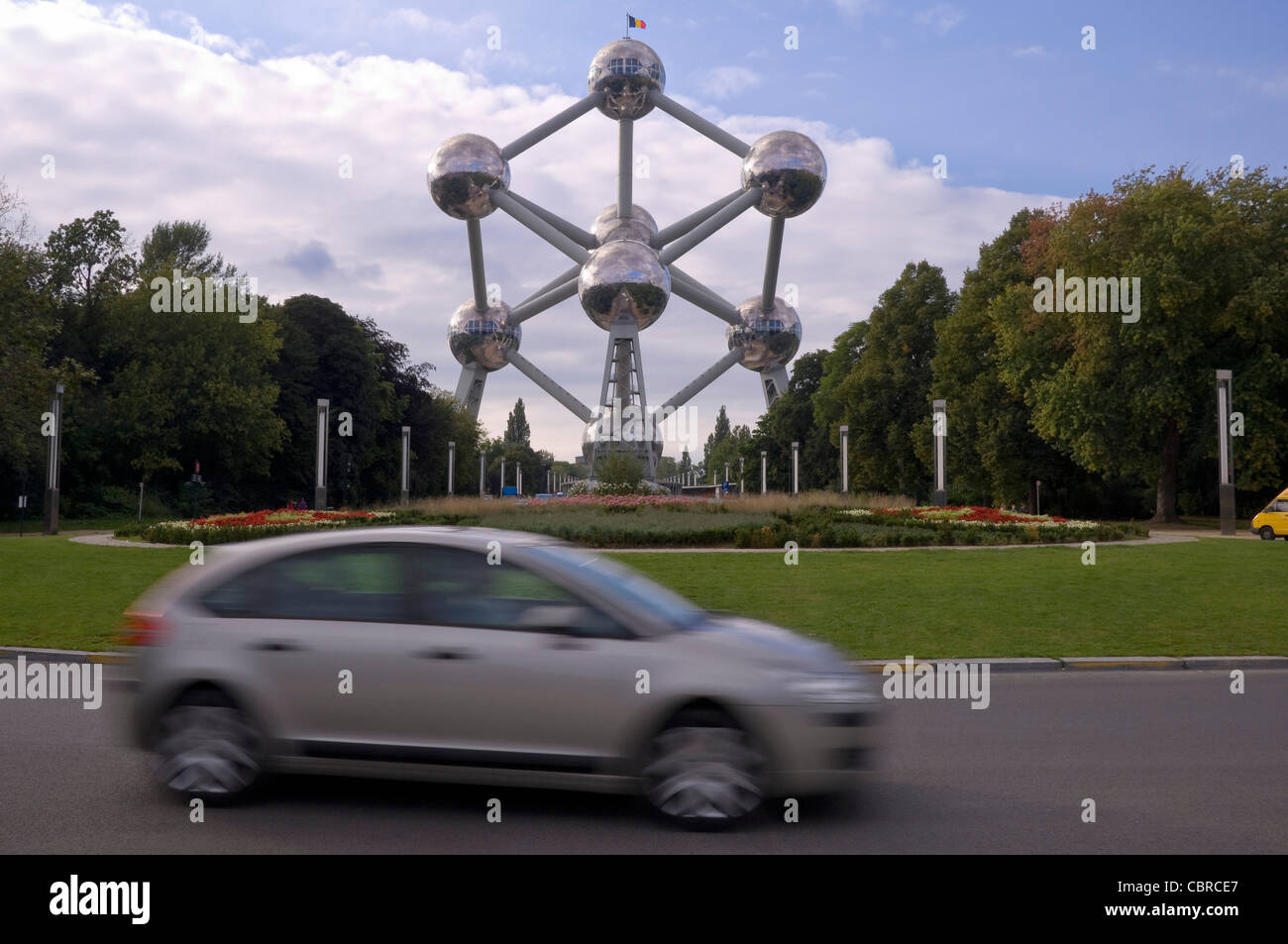 Vue horizontale de l'Atomium monument situé dans le parc du Heysel avec des voitures roulant passé sur le boulevard du Centenaire. Banque D'Images