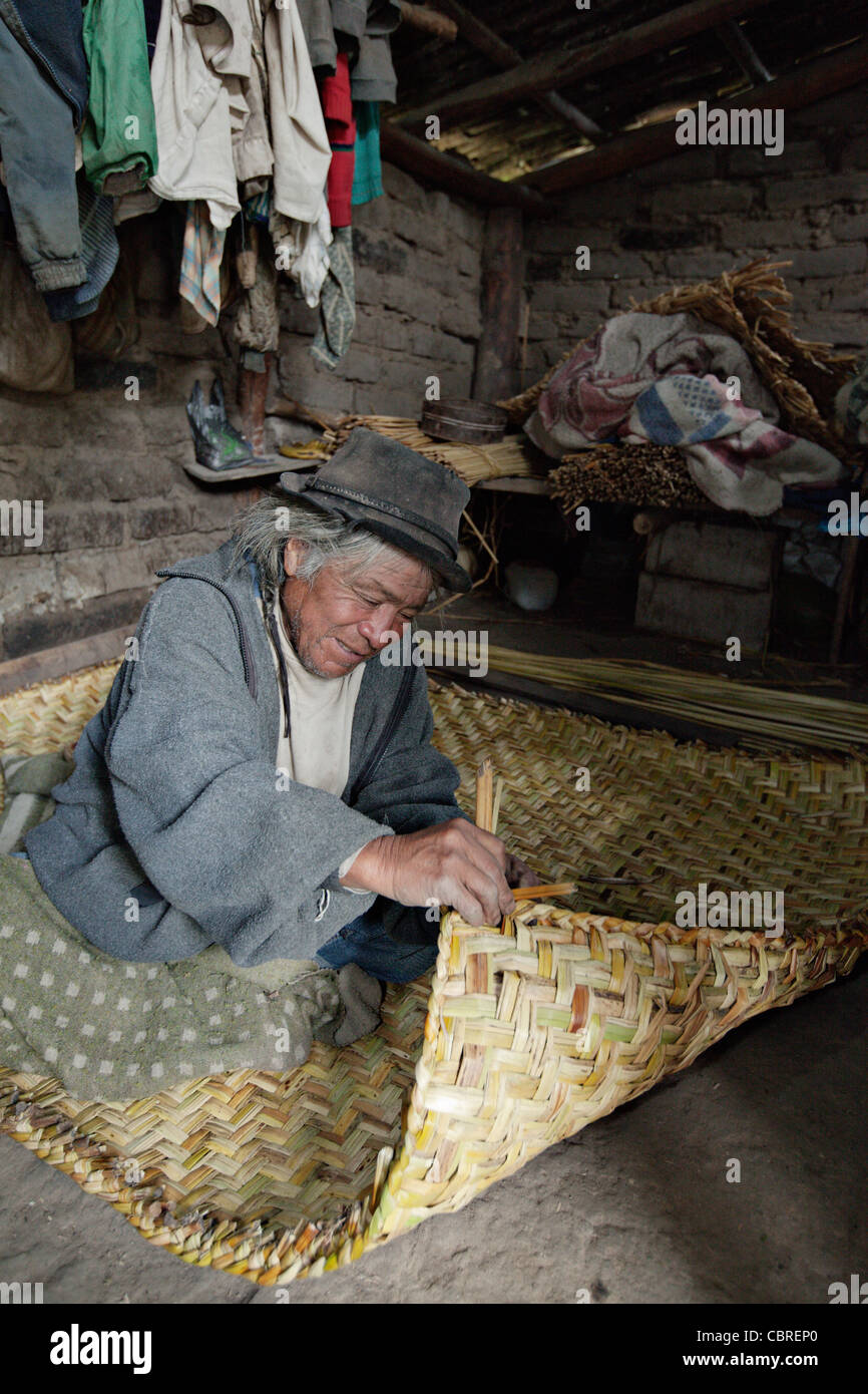 L'homme tisse un tapis de paille traditionnel dans un village près d'Otavalo, Équateur. Banque D'Images