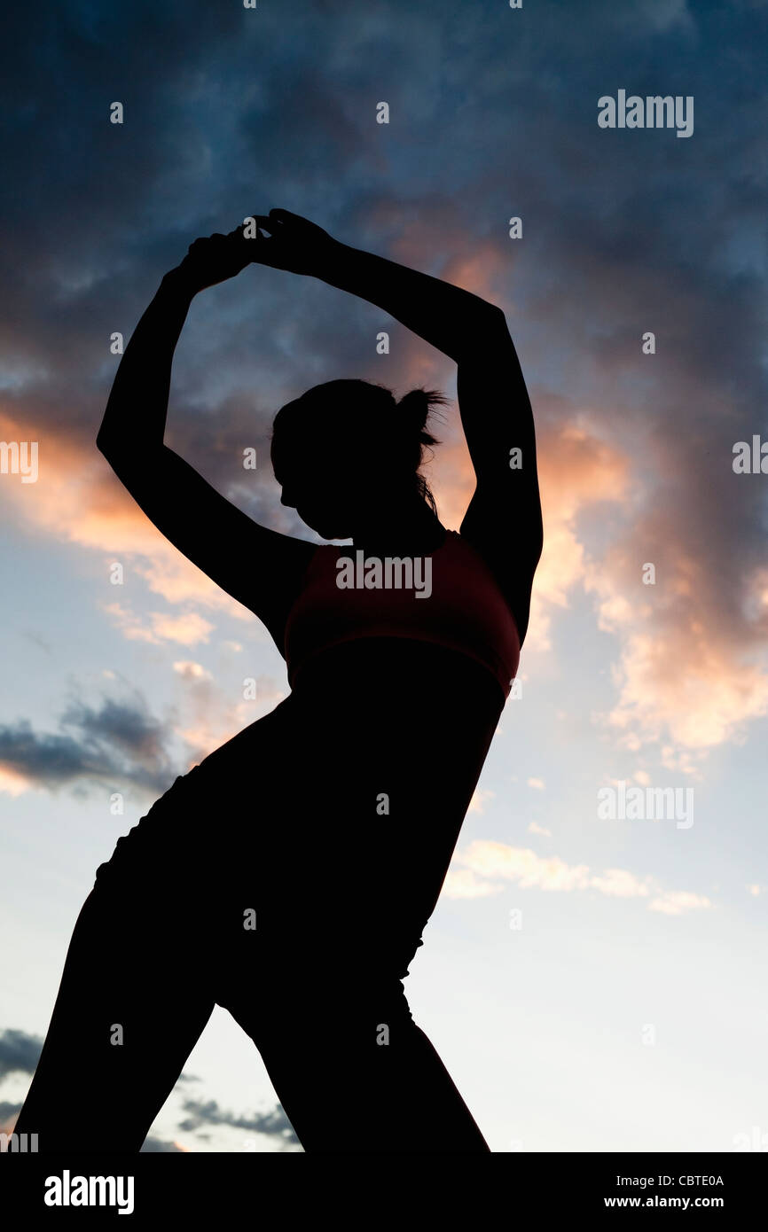 Caucasian woman stretching avant l'exercice au coucher du soleil Banque D'Images