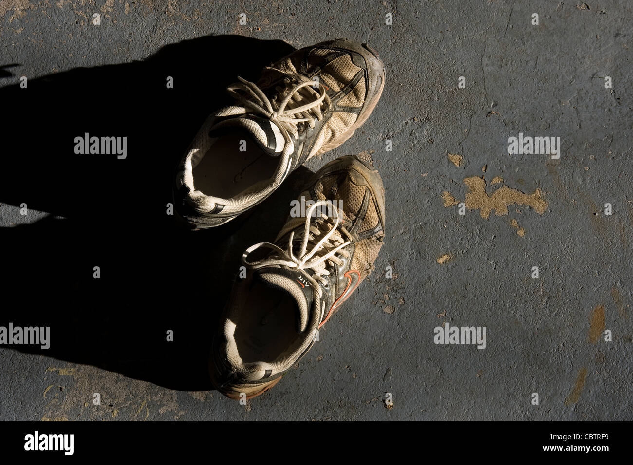 Chaussures Sneakers sale vieux, en plein soleil, un sol en béton Banque D'Images