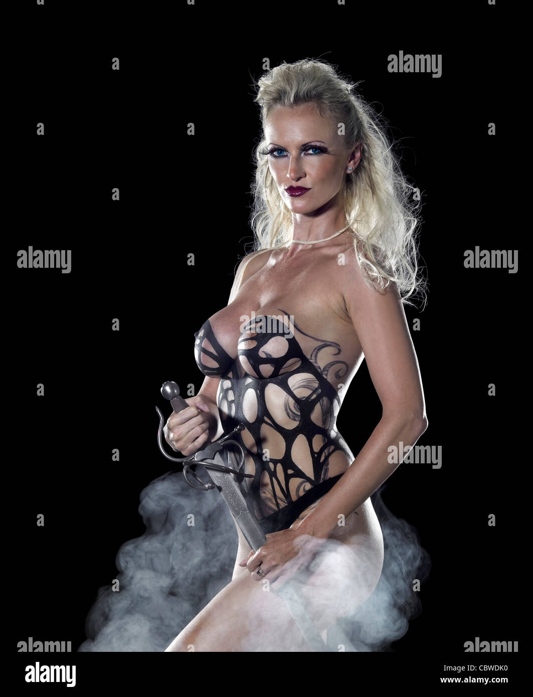 Bodypainted blonde woman posing in dark retour et un peu de brouillard Banque D'Images