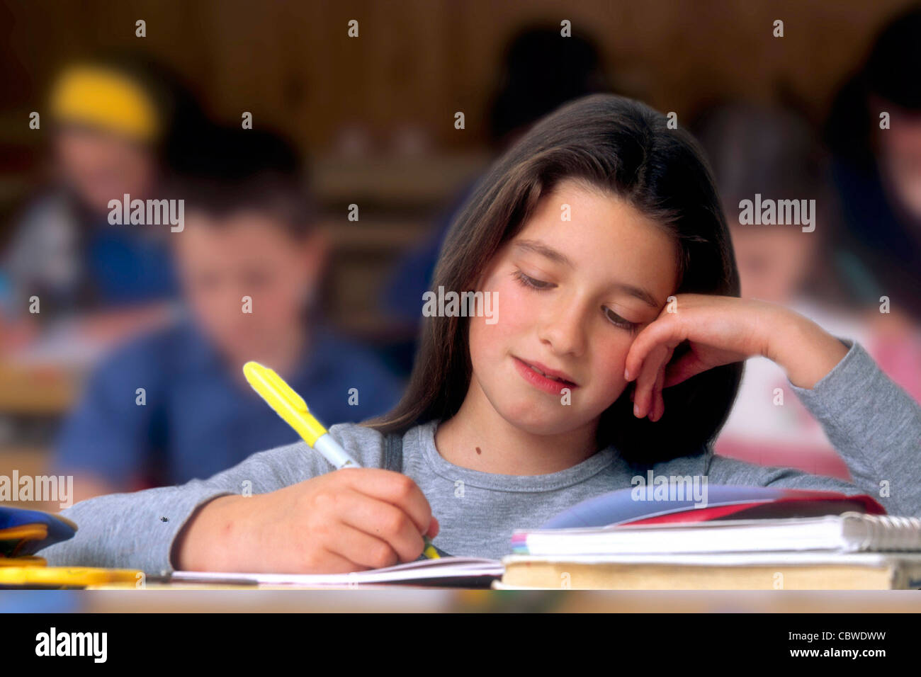 Jeune fille dans une salle de classe - petite fille dans une salle de classe pendant une leçon d'écriture. Banque D'Images
