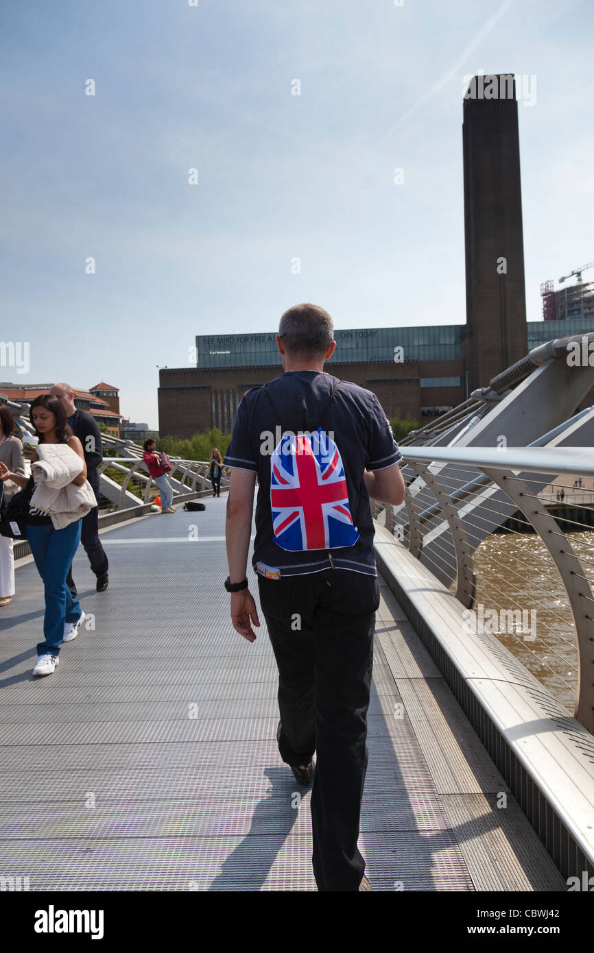 L'homme avec un sac à dos de l'union, se passant sur la passerelle du millénaire vers la Tate Modern. Banque D'Images