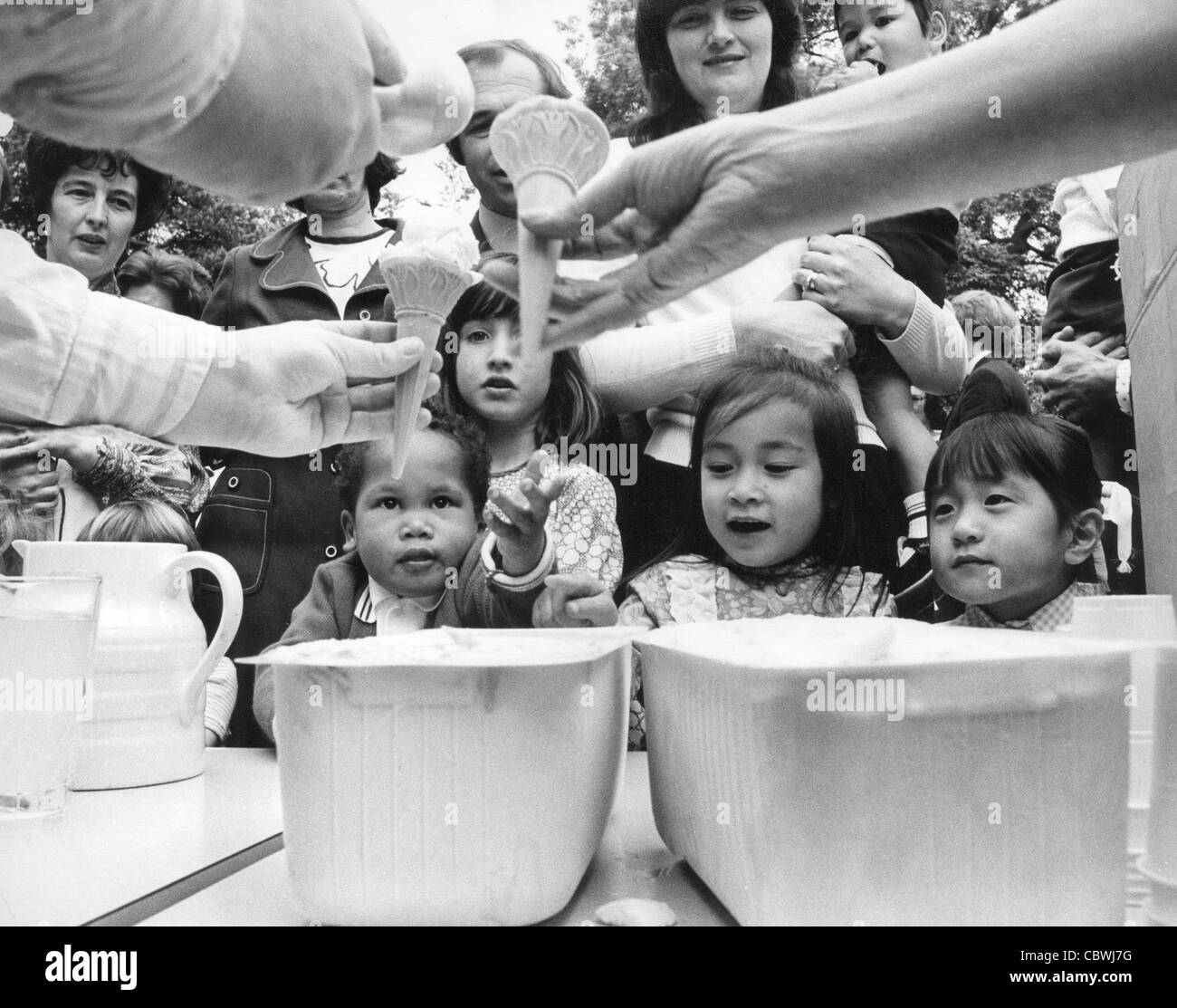Les orphelins de guerre du Vietnam tendent la main pour leur première crème glacée à une fête d'église dans l'église Stretton Shropshire 1972 photo de DAVID BAGNALL Banque D'Images