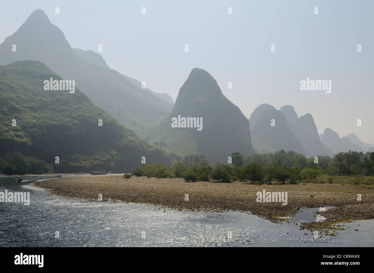 La rive de galets de la rivière Li avec pics karstiques de calcaire de reculer dans la République populaire de Chine haze Banque D'Images