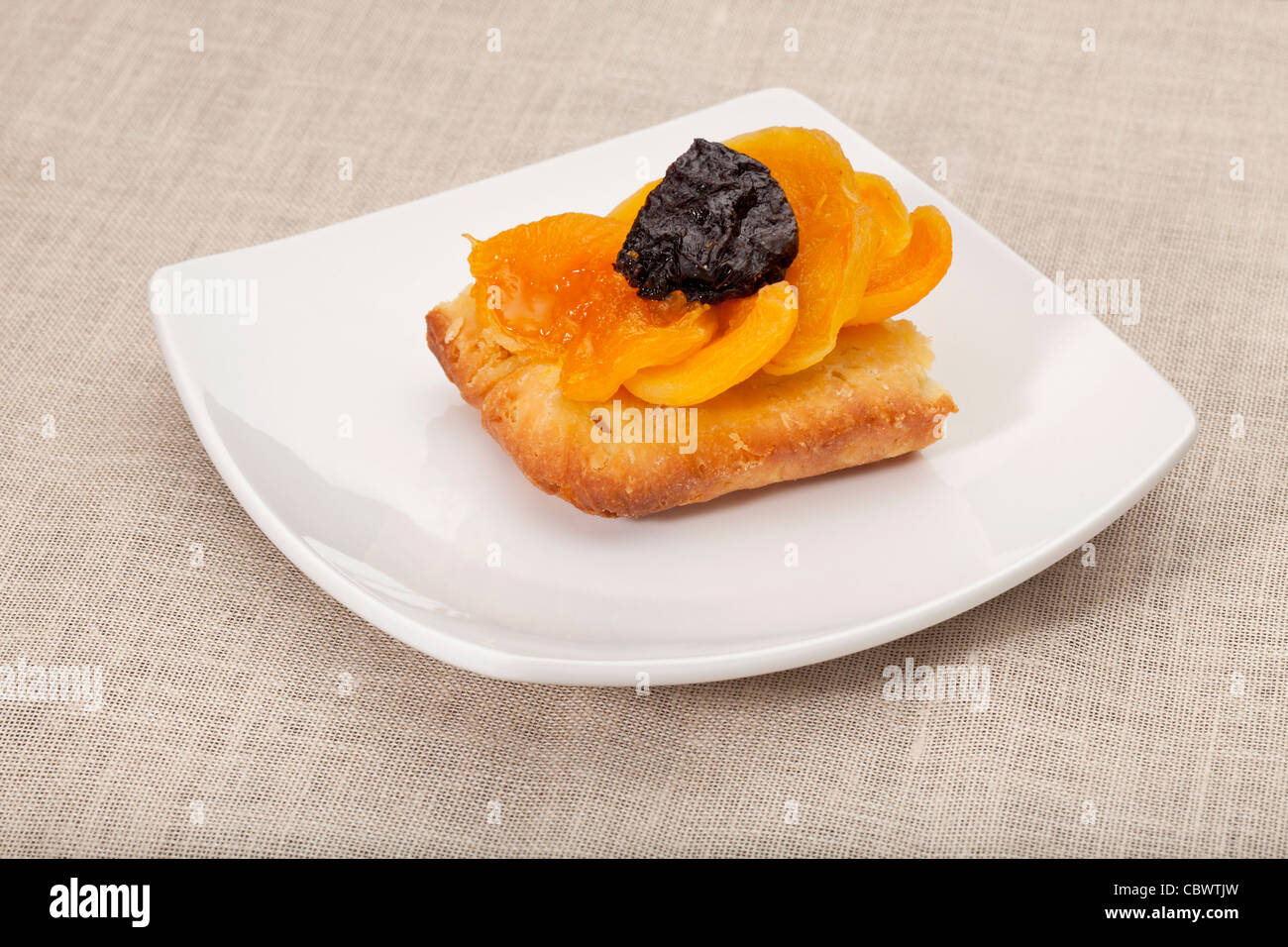 Une partie de tarte aux fruits maison abricot et prune sur une plaque carrée blanche nappe contre Banque D'Images