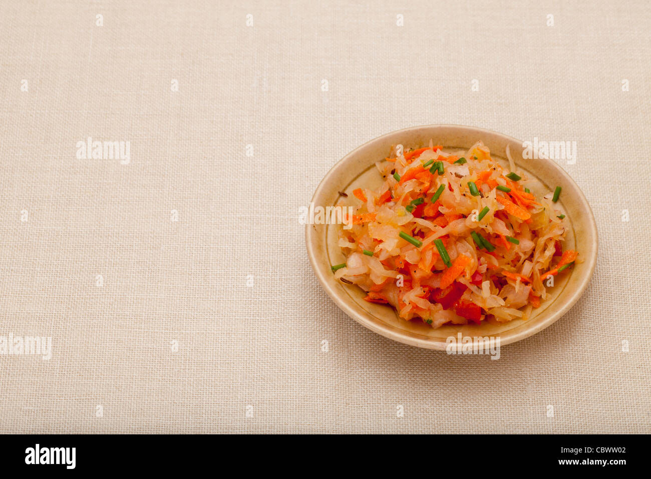 Un plat de salade de choucroute à la carotte, le poivre, la ciboulette et le carvi - un petit bol en céramique nappe contre Banque D'Images