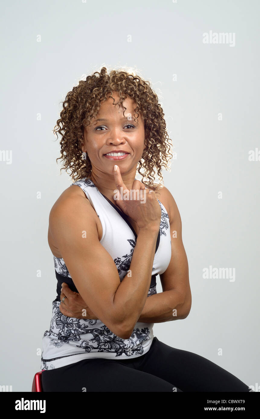 African American Woman, avec des cheveux bouclés assis et montrant ses bras puissants Banque D'Images