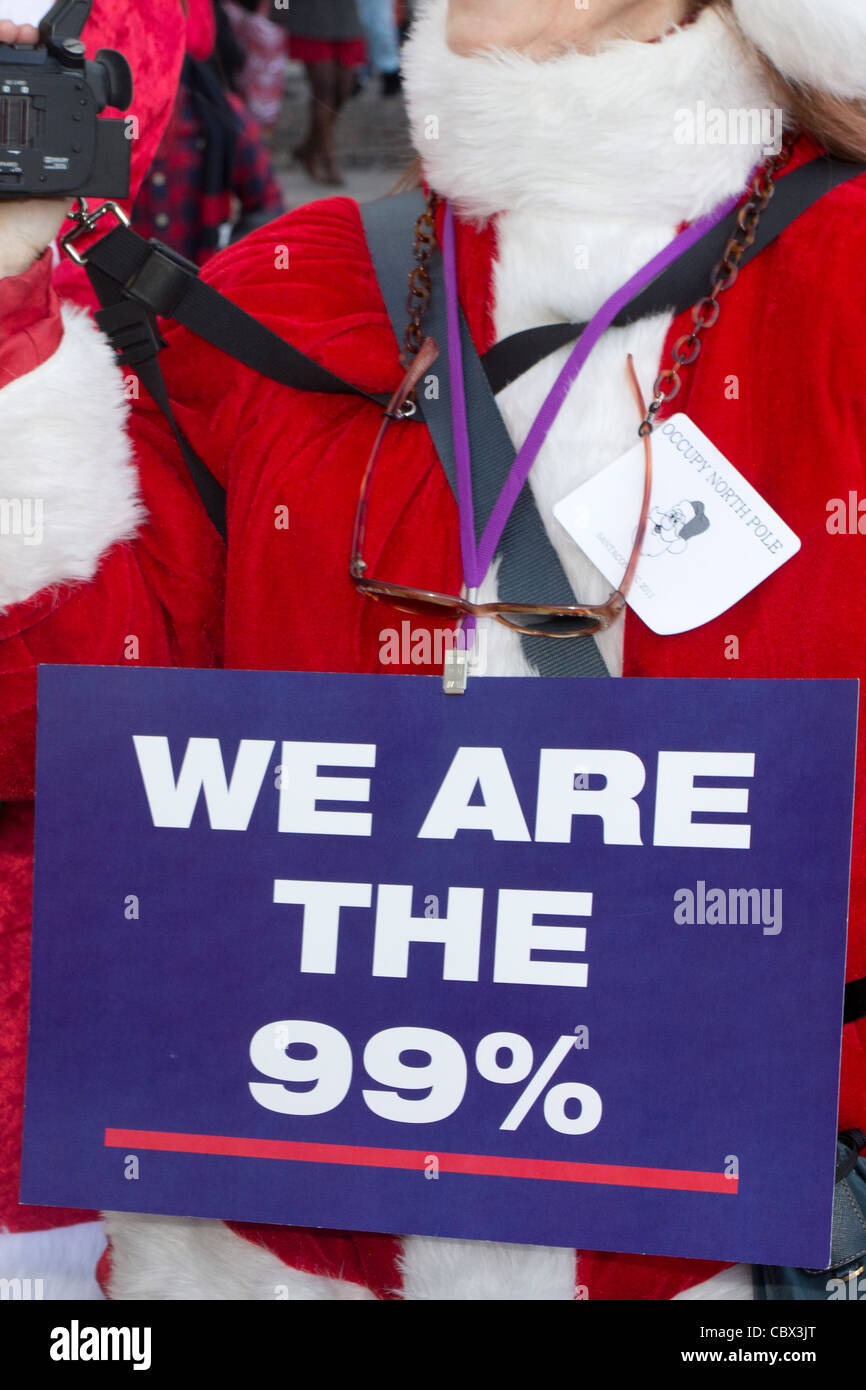 Femme habillée en père Noël portant un 'Nous sommes les 99 %' affiche de la Santacon 2011 au World Financial Center à New York Banque D'Images