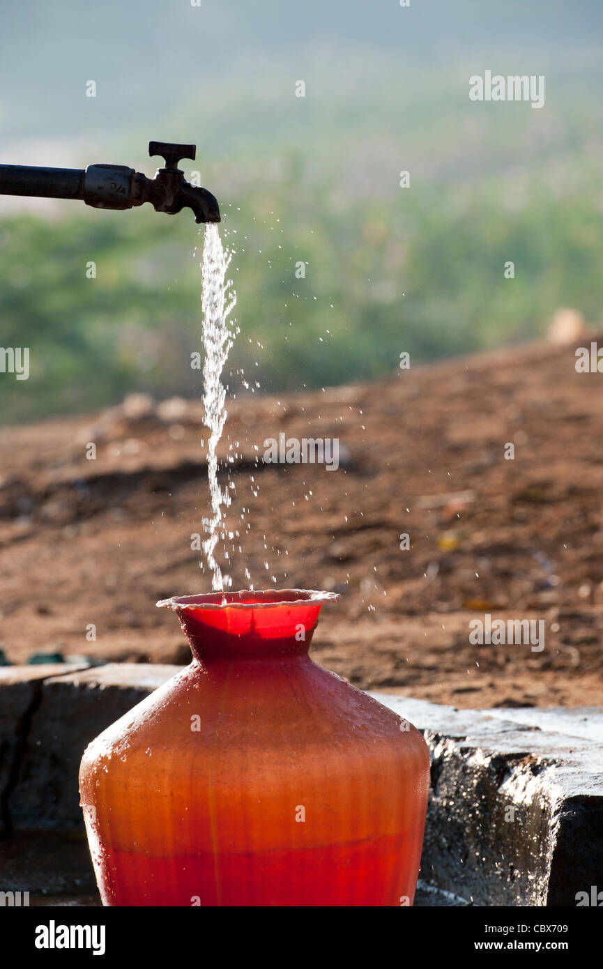 L'eau des indiens à tuyau remplissage d'un pot d'eau en plastique. L'Andhra Pradesh, Inde Banque D'Images