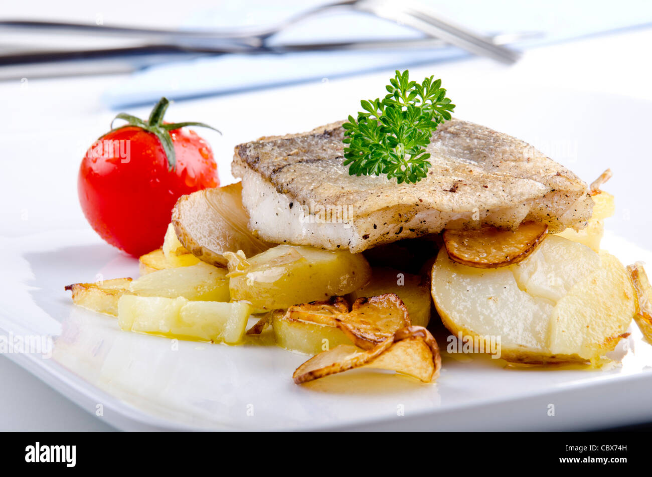 Filet d'aiglefin grillé sur une plaque avec de l'ail et de pommes de terre Banque D'Images