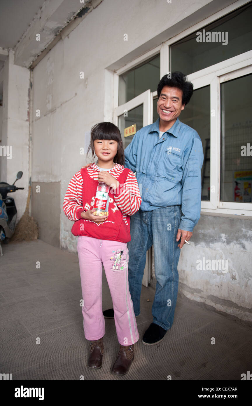 Père et fille en face de l'entrée d'une résidence pour les travailleurs d'usine dans une banlieue de Pékin. Banque D'Images