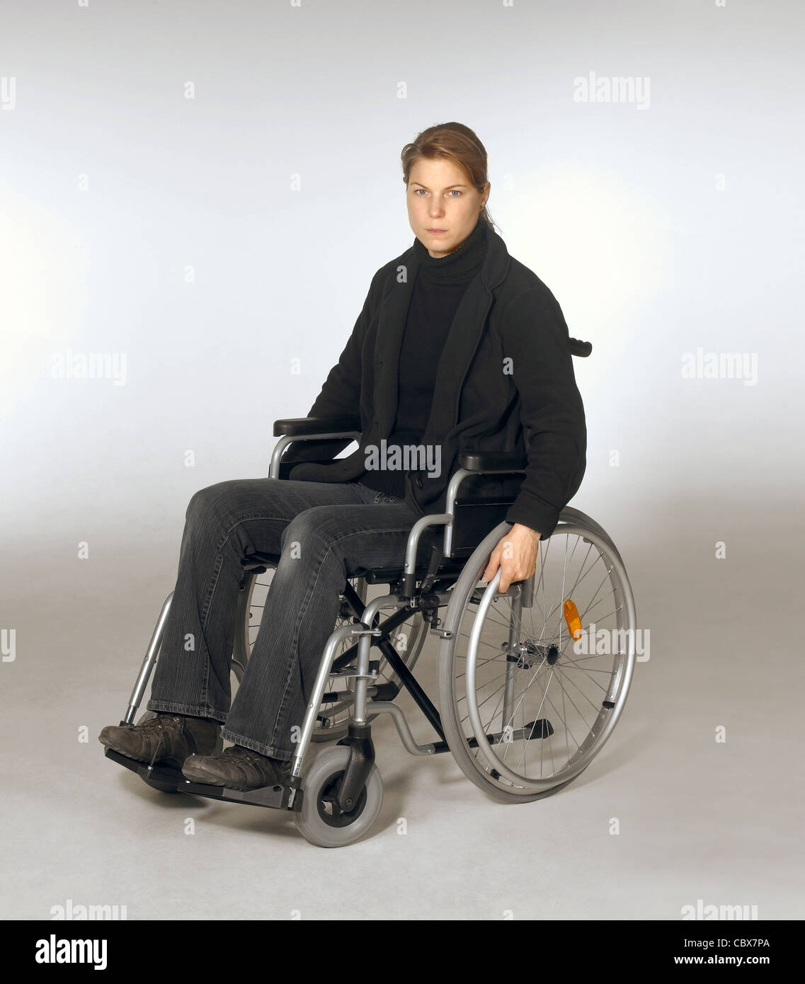 Portrait d'une jeune femme en fauteuil roulant en gris clair retour Banque D'Images