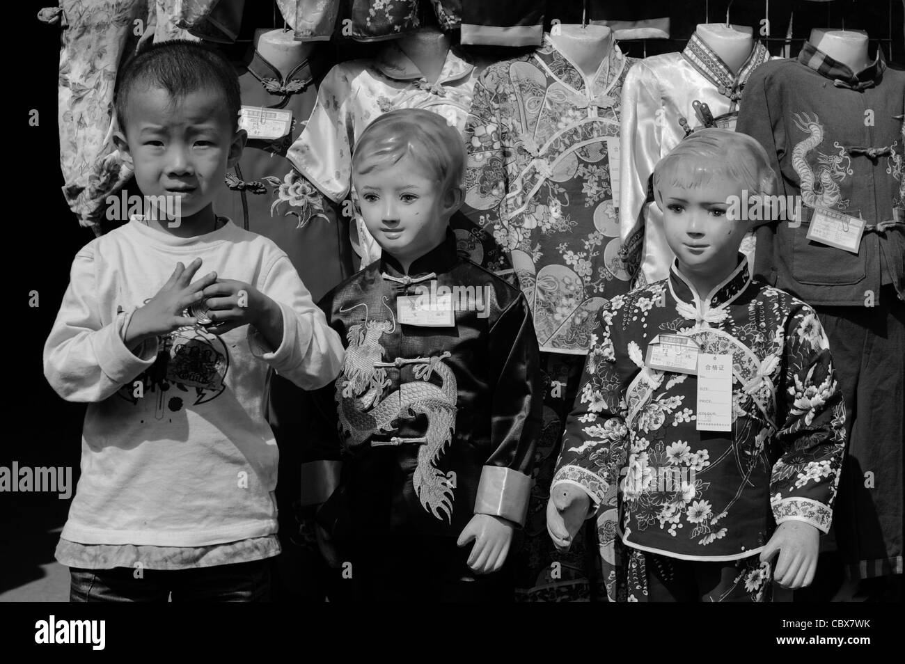 Pingyao, Chine. Garçon avec des mannequins en face d'un magasin de vêtements. Banque D'Images