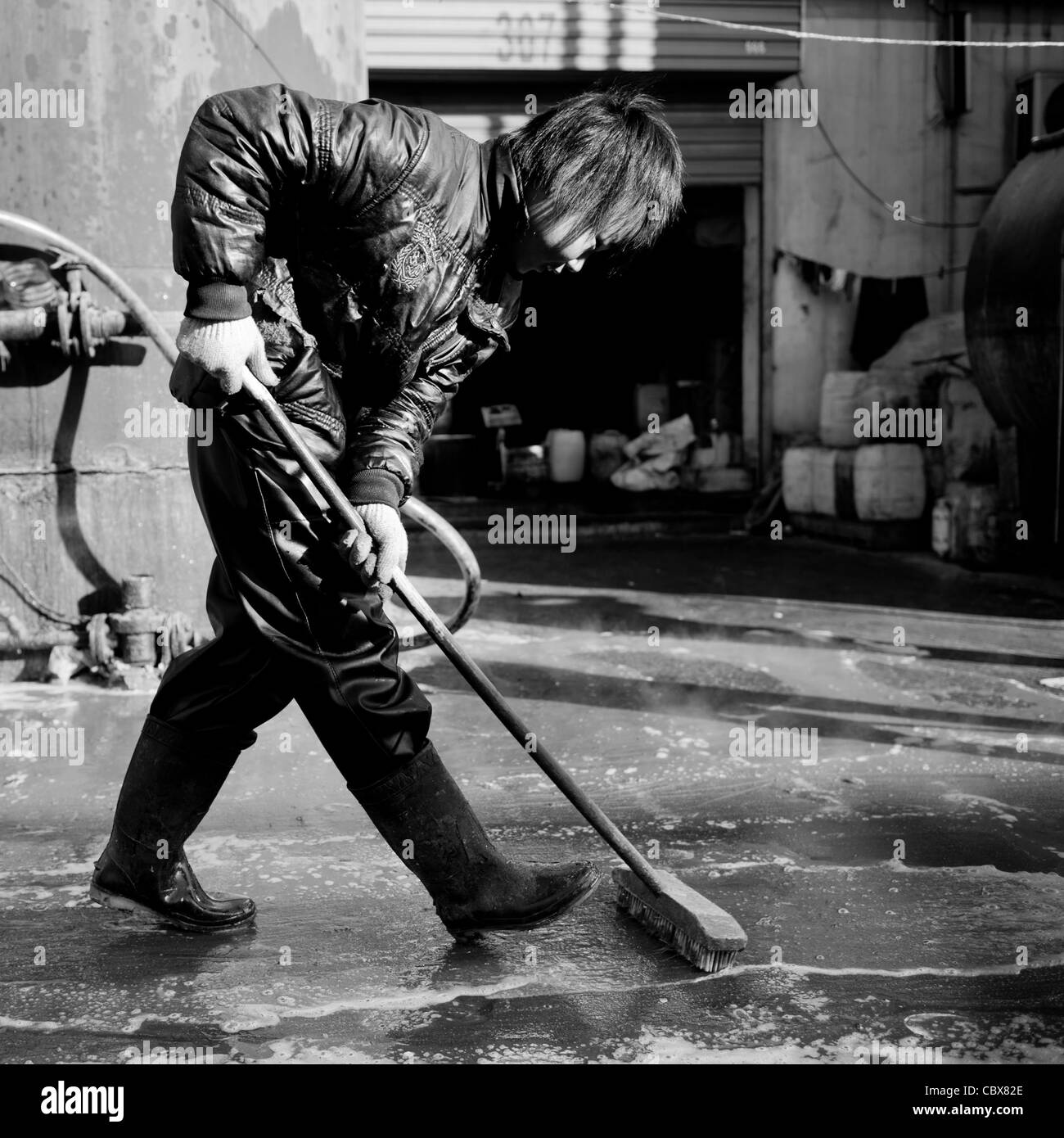 DongBaXiang, Beijing. Jeune homme travaillant dans une usine de recyclage de l'huile de cuisson. Banque D'Images