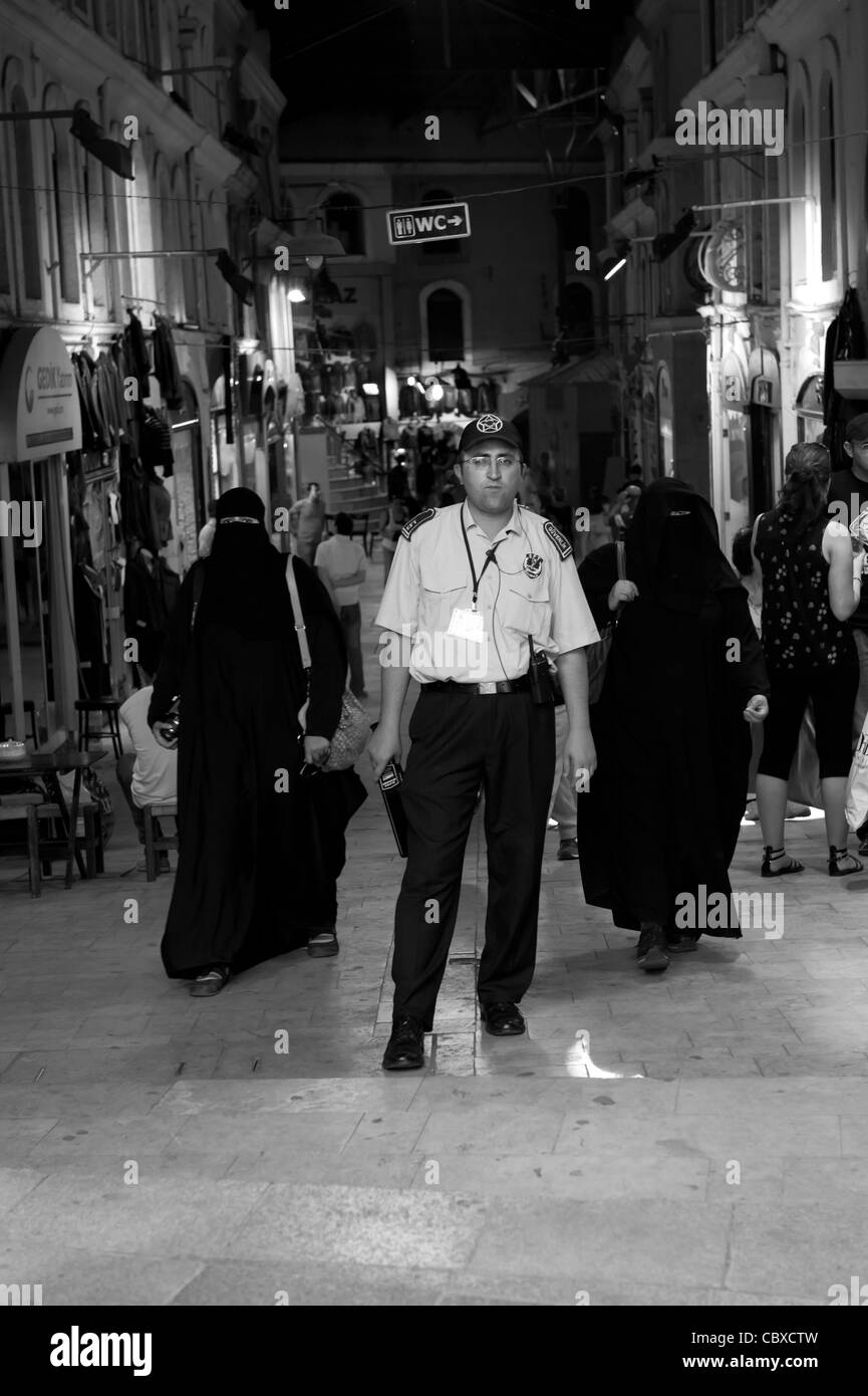 Le Grand Bazar, Istanbul. Garde de sécurité et deux femmes voilées dans la rue. Banque D'Images