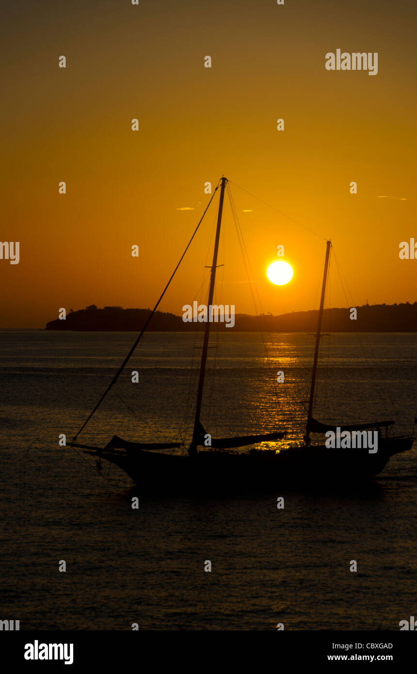 GALLOWS POINT, doté John, Îles Vierges américaines — Un voilier à deux mâts est silhouetté contre le soleil couchant alors qu'il est amarré dans les eaux calmes au large de Gallows point sur le nouveau John, Îles Vierges américaines. Cette scène pittoresque capture le mélange de tradition nautique et de beauté naturelle qui caractérise l'île des Caraïbes. Banque D'Images