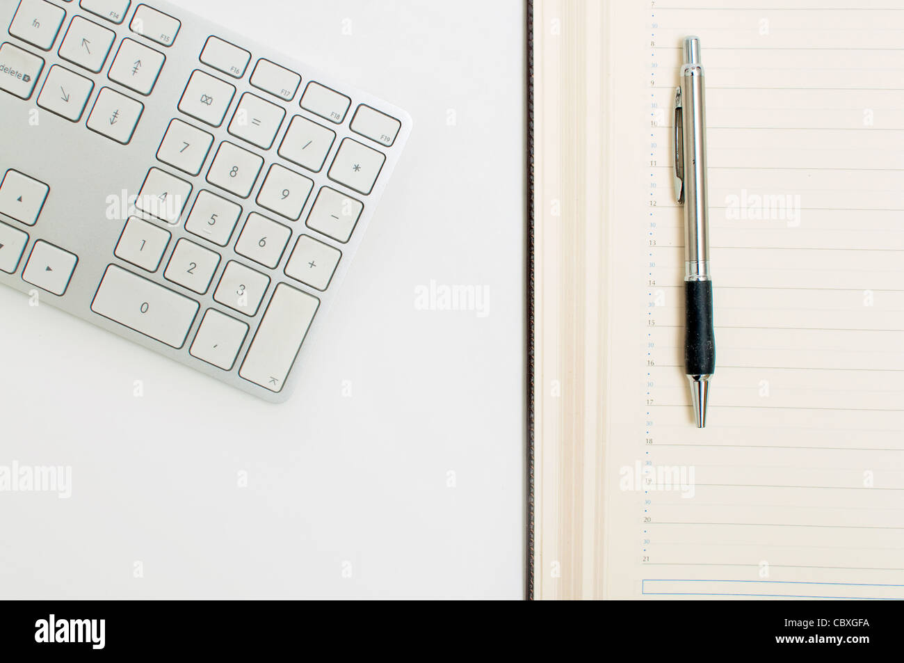 Détail de bureau, un clavier d'ordinateur, de l'ordre du jour et d'un stylo sur une table blanche. Concept d'entreprise. Banque D'Images
