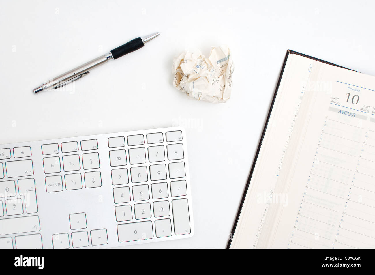 Détail de bureau, un clavier d'ordinateur, de l'ordre du jour et d'un stylo sur une table blanche. Concept d'entreprise. Banque D'Images