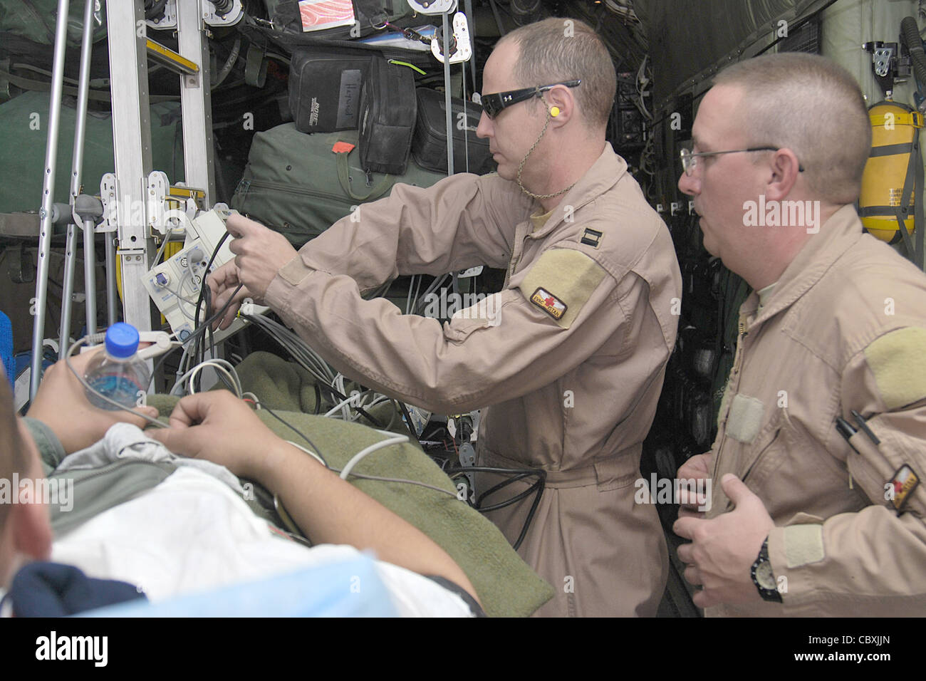 Membres de l'équipe de transport aérien en soins intensifs, le capitaine John Eggert et le sergent-chef. Rich Pakula a installé de l'équipement médical pour son patient à l'intérieur d'un Hercules C-130H le 5 janvier 2011, à l'aérodrome de Kandahar, en Afghanistan. La CCATT est une équipe spécialisée de trois personnes qui recrée un environnement d'unité de soins intensifs dans un avion pendant les évacuations aéromédicales. Le capitaine Eggert est infirmière et le sergent Pakula est un technicien respiratoire affecté au 451e Escadron d’évacuation aéromédicale expéditionnaire. Banque D'Images