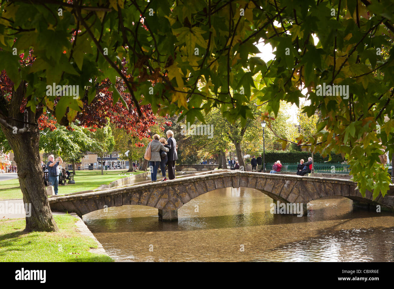 Les touristes qui pose pour des photos dans le village de Cotswold Bourton On The Water, Gloucestershire Banque D'Images