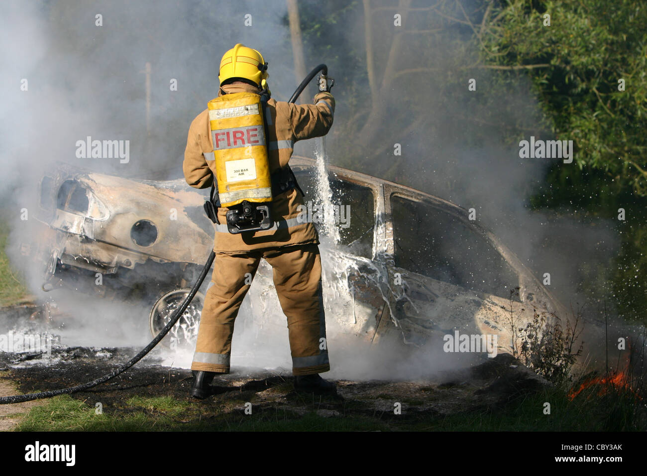 Le tuyau d'incendie éteint une voiture en feu d'un tuyau, d'un feu et d'une auto. Un pompier éteint un incendie de voiture Banque D'Images