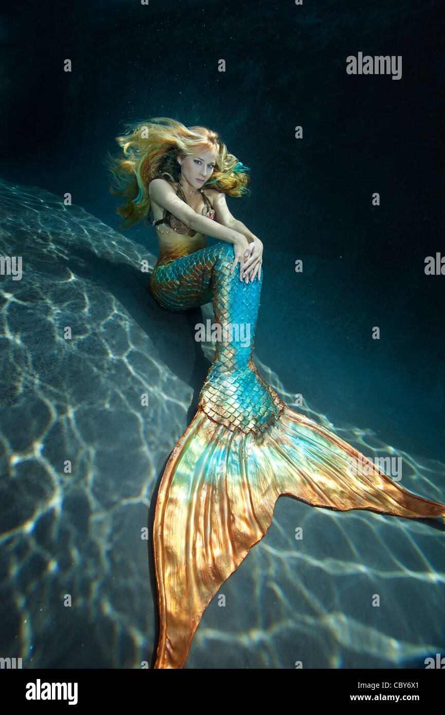 Jeune sirène assis sous l'eau avec ses mains sur sa queue Banque D'Images
