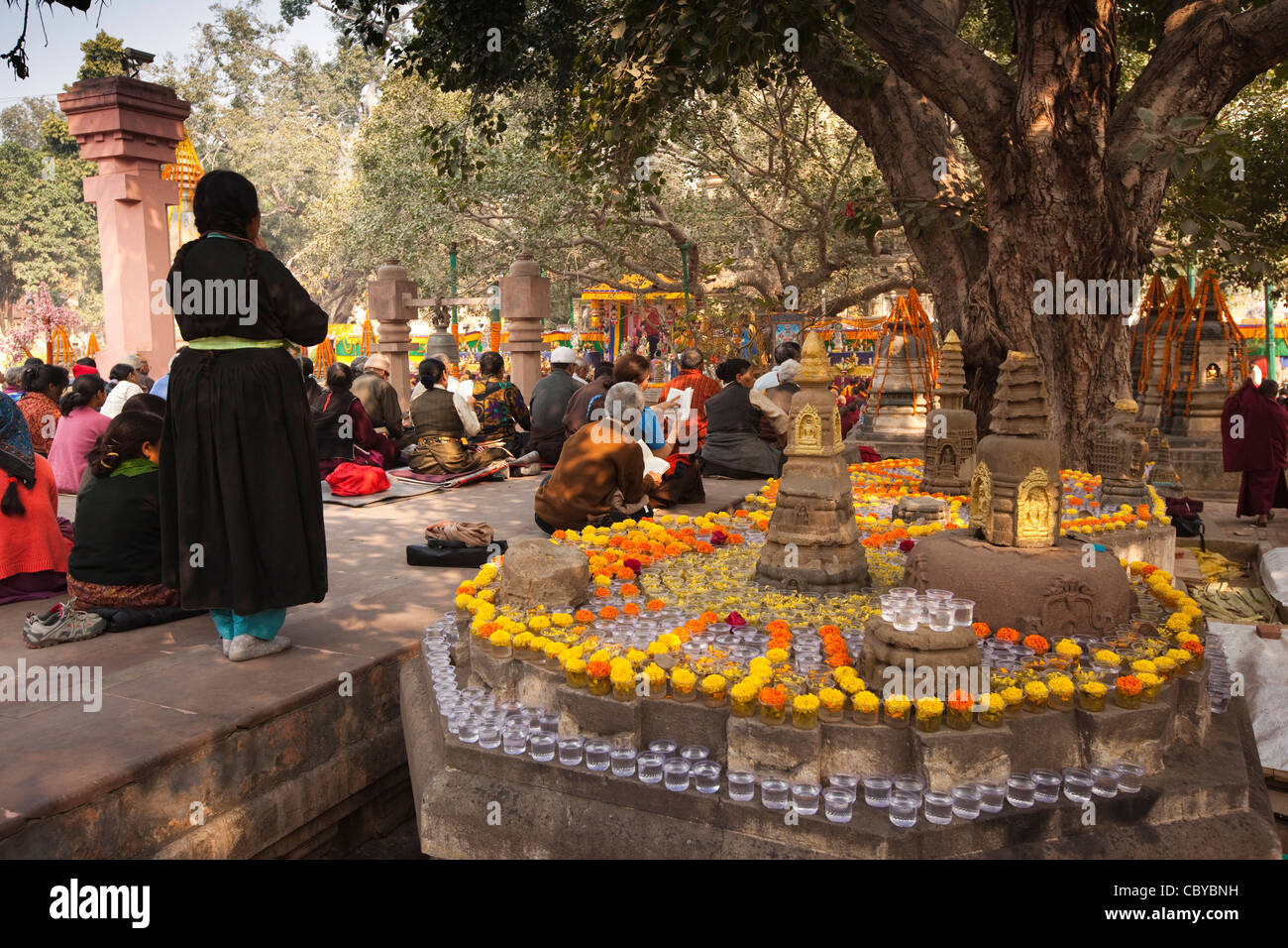 L'Inde, le Bihar, le Temple de la Mahabodhi Bodhgaya, pèlerins priant parmi les offrandes florales dans la cour intérieure Banque D'Images